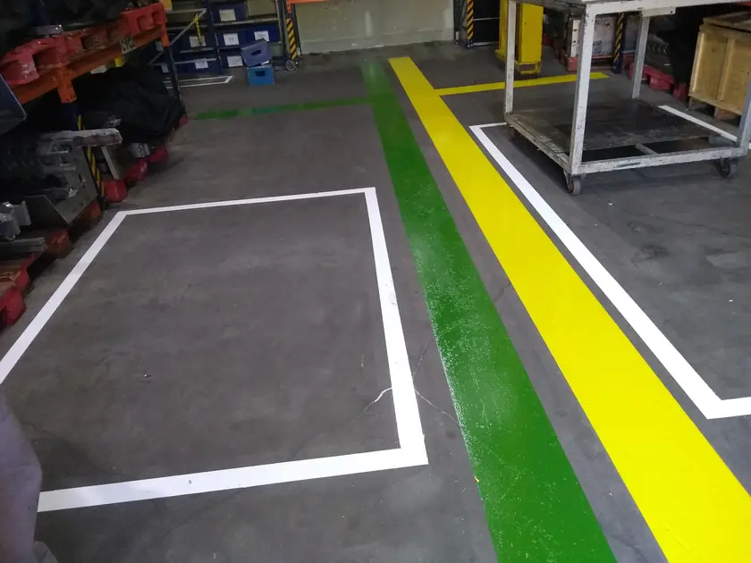 Demarcação de piso industrial com faixas em verde, amarelo e branco
